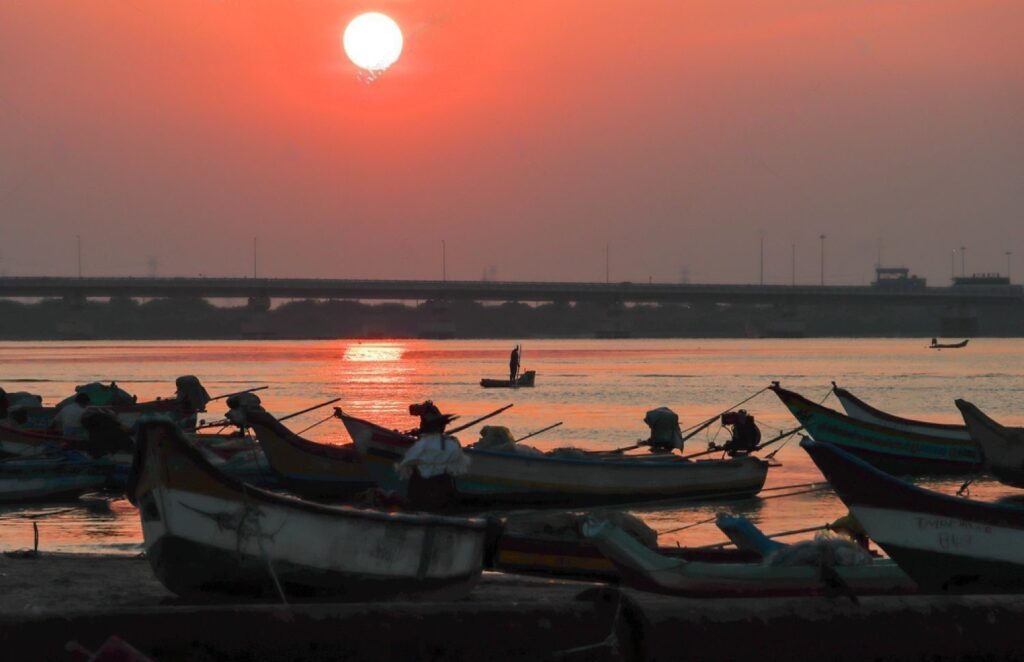 Beautiful Sunset with Orange sky and Fishing Boat silhouette at Ennore Nettukuppam Boatyard North Chennai, Tamil Nadu in India