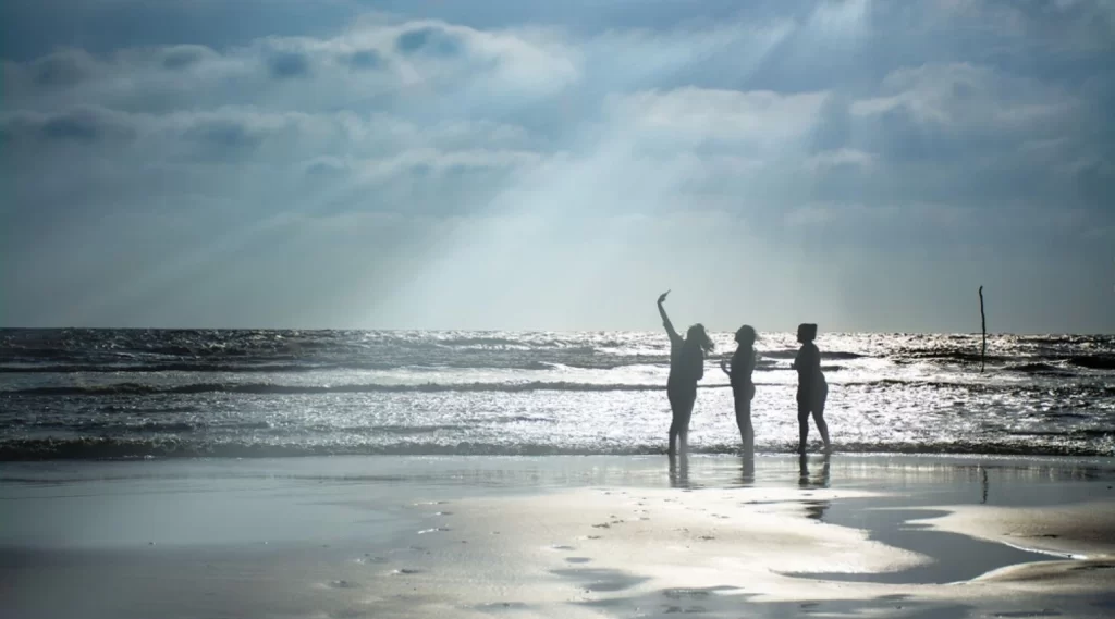 Girls taking selfee on suvali beach in the evening with backlit sun and beautiful rays coming through the clouds