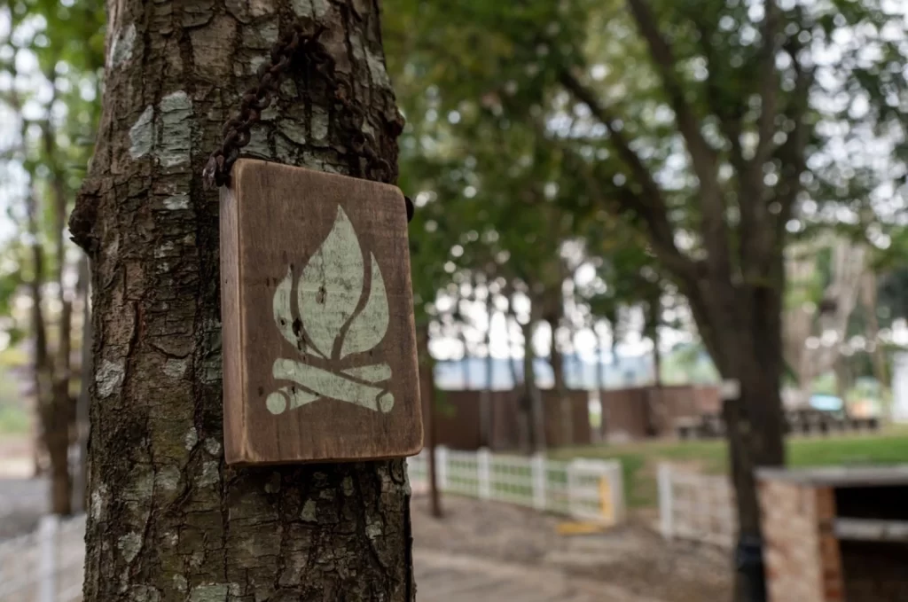 Wooden Camp fire icon. Bonfire burning on firewood signage in this area hang on the big tree.